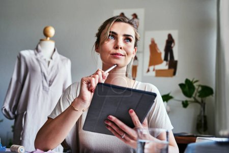 Photo for The sky is the limit when you start thinking creatively. a fashion designer using a digital tablet while sitting in her workshop - Royalty Free Image