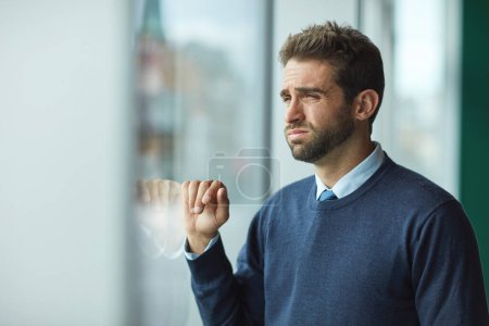 Photo for Someone get me out of here. a handsome young businessman standing indoors alone and looking stressed - Royalty Free Image