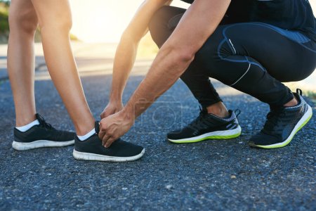 Photo for Date someone wholl always have your back. a man typing his girlfriends laces while out for a run - Royalty Free Image