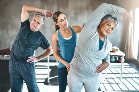 Photo for Stretching, helping and senior people with personal trainer in class for fitness, wellness or rehabilitation. Health coach, workout or retirement with elderly patient, man or female in gym warm up. - Royalty Free Image