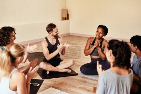Téléchargez les photos : Rien n'est plus contagieux que la motivation. un groupe de jeunes hommes et femmes applaudissant pendant un cours de yoga - en image libre de droit