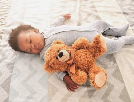 Foto de Dormir, oso de peluche y siesta con bebé en el dormitorio para el cansancio, el desarrollo y la inocencia. Soñar, relajarse y cómodo con el bebé africano y el juguete en casa para la mañana, el descanso y la hora de dormir. - Imagen libre de derechos