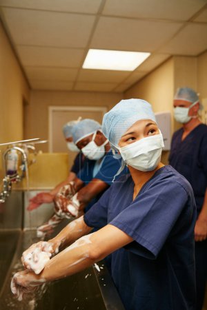 Photo for Maintaining cleanliness and hygiene between each operation. a team of surgeons sterilizing their arms and hands as part of a surgical routine - Royalty Free Image