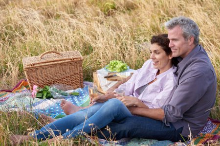 Photo for Nothing more romantic than a picnic. A loving mature couple enjoying an intimate picnic together in a scenic field - Royalty Free Image