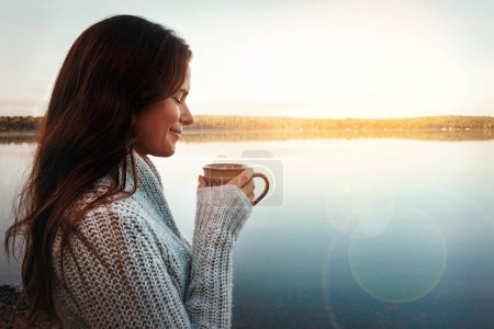 Téléchargez les photos : Un bon café, c'est tout. une jeune femme séduisante passant du temps seule au bord du lac - en image libre de droit