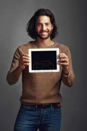 Foto de Reconozco una buena aplicación cuando la veo. Captura de estudio de un joven guapo sosteniendo una tableta digital con una pantalla en blanco sobre un fondo gris - Imagen libre de derechos
