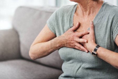 Herzinfarkt, Brustschmerzen und eine kranke Seniorin mit Asthma im heimischen Wohnzimmer oder auf der Couch im Notfall. Krise, medizinische und ältere Menschen mit Beschwerden aufgrund von Krankheit oder Atemproblemen.