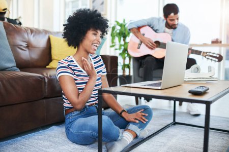 Photo for Couples have their own interests, and thats ok. a woman using her laptop while her boyfriend plays the guitar in the background - Royalty Free Image