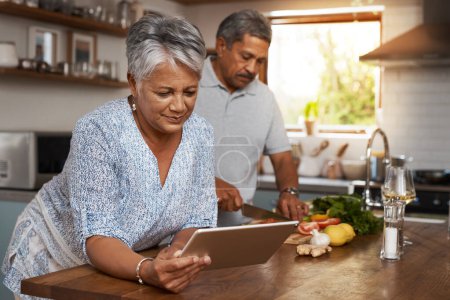 Photo for Senior couple, tablet and cooking in kitchen with healthy food, online search and app for nutrition in home. Digital recipe, old woman and man in house with meal prep, wellness and retirement diet - Royalty Free Image