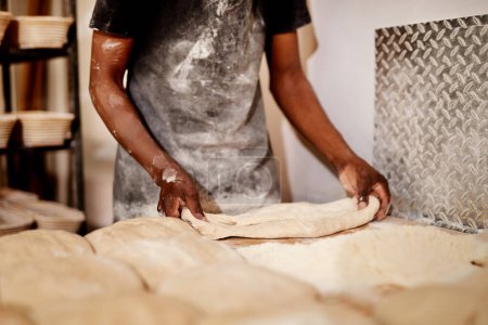Foto de No usamos más que los mejores ingredientes. un panadero masculino ocupado moldeando masa en el trabajo - Imagen libre de derechos