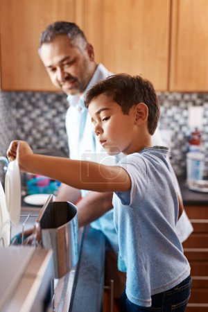 Photo for Home, father and son washing dishes, family and help with development, cleaning and chores. Male parent, dad and son in the kitchen, teaching skills and growth with bonding, learning and cooperation. - Royalty Free Image