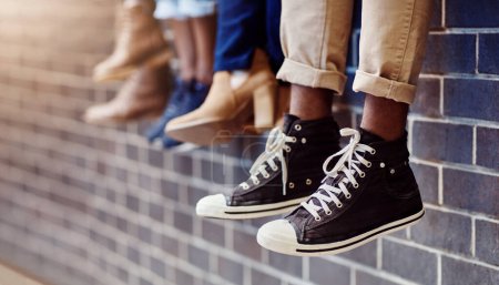 Photo for Brick wall, student sneakers and friends outdoor on university campus together with shoes. Relax, youth and foot at college with people legs ready for education, study and urban feet while sitting. - Royalty Free Image