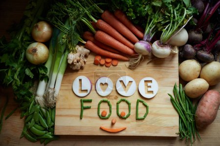 Foto de Recién salido de la tierra. Bodegón de una variedad de verduras en una tabla de cortar con el mensaje de amor y comida - Imagen libre de derechos