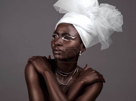 Foto de Es un símbolo de la belleza africana. Captura de estudio de una atractiva joven posando en traje tradicional africano sobre un fondo gris - Imagen libre de derechos