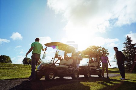 Téléchargez les photos : Qui monte en premier. amis jouant une partie de golf sur un fairway - en image libre de droit