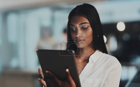 Photo for Surfing the net for a little inspiration. a young businesswoman using a digital tablet in an office at night - Royalty Free Image