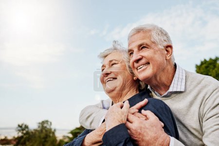 Sky, elderly couple and hug outdoors or happy in retirement or husband and wife in nature. Mature, man and woman smile in vacation or senior citizens care and embrace or date at the park for romance.
