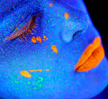 Neonfarbe, Make-up-Zoom und Frauengesicht mit schwarzem Hintergrund und kreativer Kosmetik. Glühen Schönheit, Fantasie und psychedelische Kosmetik eines weiblichen Modells mit einzigartigen und Kreativität mit Kunst im Atelier.
