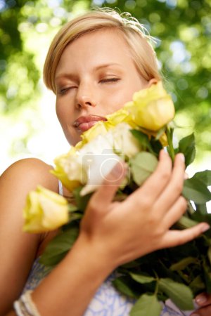Foto de Nunca puedes equivocarte con las rosas. una hermosa joven de pie afuera sosteniendo un ramo de rosas amarillas - Imagen libre de derechos