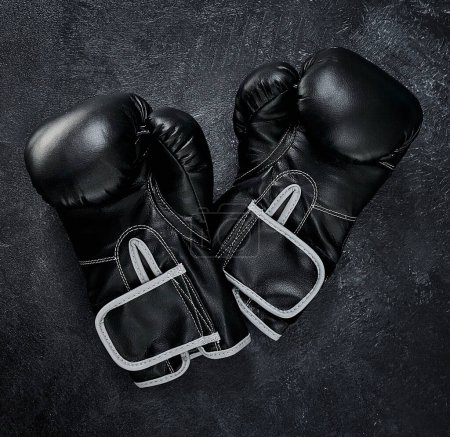Photo for Put your hands up. High angle shot of a pair of boxing gloves placed together on top of a dark background inside of a studio - Royalty Free Image