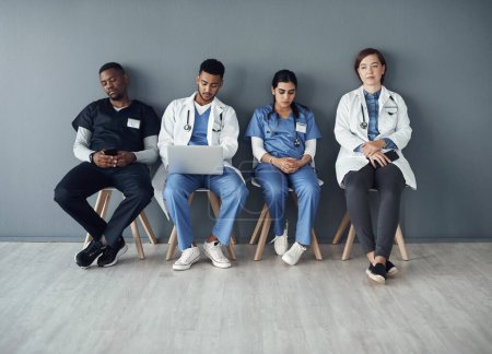 Foto de Aprecio a todos los médicos que nos salvaron. un grupo de médicos sentados sobre un fondo gris en el trabajo - Imagen libre de derechos