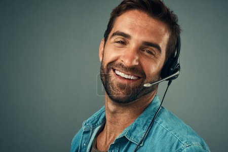 Photo for Happy man, portrait and headphones for call center consulting against a grey studio background. Face of friendly male consultant agent with smile and headset in contact us for help or online advice. - Royalty Free Image