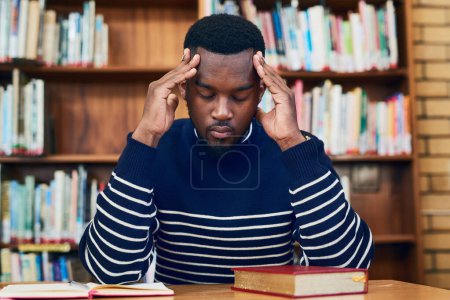 Foto de I have to start focusing. a university student looking stressed while sitting in the library - Imagen libre de derechos