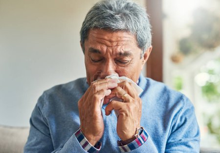 Photo for Senior man, sick and blowing nose in home from virus, allergy and illness on couch. Tired, tissue and elderly male person in a house lounge with sneeze from covid and flu on a sofa with allergies. - Royalty Free Image