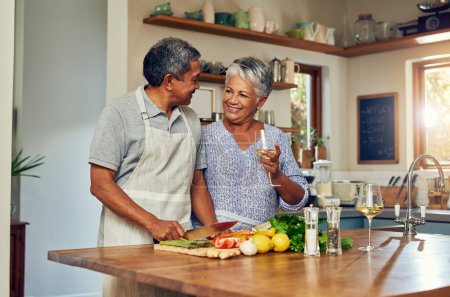 Love, cooking and old couple with wine in kitchen, healthy food and marriage bonding together in home. Drink, glass and senior woman with man, meal prep and vegetables for wellness diet in retirement.
