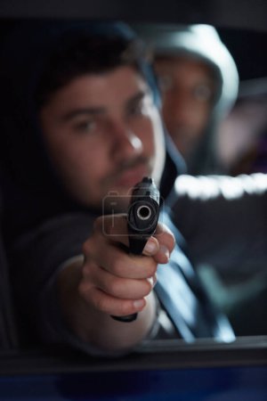 Téléchargez les photos : Le crime est réel. deux hommes assis dans une voiture et pointant une arme - en image libre de droit