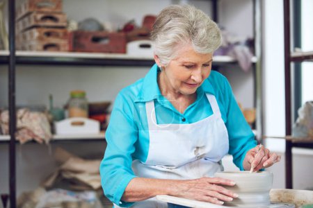 Téléchargez les photos : Elle fait ce qu'elle aime. une femme âgée fabriquant un pot en céramique dans un atelier - en image libre de droit