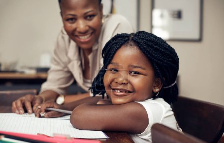 Foto de Soy la chica inteligente de las mamás. Retrato de una adorable niña sonriendo mientras hacía sus deberes con su madre en casa - Imagen libre de derechos