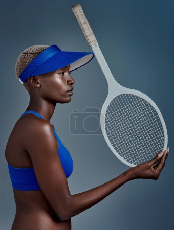 Téléchargez les photos : Je suis un pro du tennis. Plan studio d'une jeune femme sportive posant avec une raquette de tennis sur fond gris - en image libre de droit