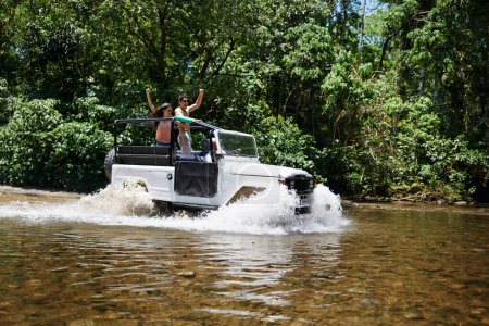Téléchargez les photos : Faire leur voyage sur un terrain extrême. un jeune couple traversant une rivière dans son véhicule hors route - en image libre de droit