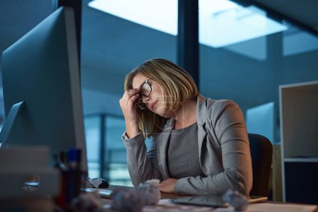 Téléchargez les photos : Ses yeux se fatiguent. une femme d'affaires qui a l'air stressée en travaillant tard au bureau - en image libre de droit