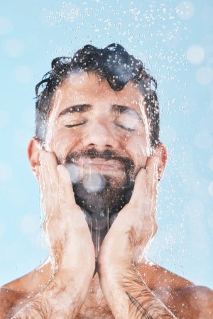 Foto de Wellness, water or man in shower cleaning skin or washing face and body in morning grooming routine in studio. Blue background, hands or healthy male model with self care, self love or a happy smile. - Imagen libre de derechos