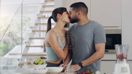 Photo for Love, cooking and couple kissing in kitchen while preparing a healthy, fresh and diet breakfast. Happy, bonding and young man and woman with intimate moment while cutting fruit for smoothies together. - Royalty Free Image