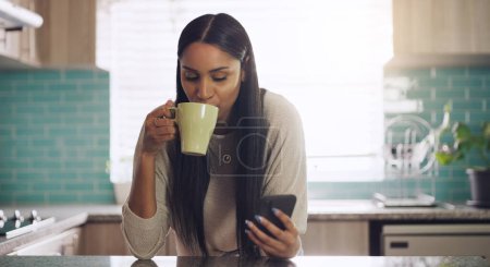 Photo for Phone, texting and woman with coffee in a kitchen relax with social media, app or reading. Smartphone, streaming and female drinking tea in her home in the morning, calm and peaceful in her apartment. - Royalty Free Image