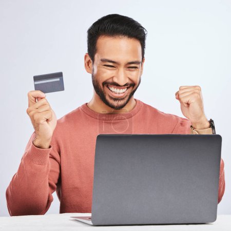 Photo for Excited man, laptop and credit card for online shopping, e commerce and payment in studio. Asian male person with technology and hand to celebrate savings, promotion or sale on a fintech website. - Royalty Free Image
