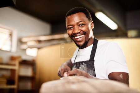 Téléchargez les photos : Je m'amuse avec ce que je fais. un boulanger mâle retirant du four du pain fraîchement cuit - en image libre de droit