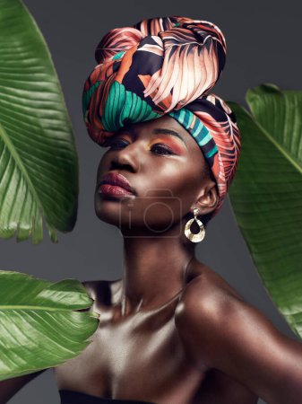 Foto de Mujer negra en turbante tradicional, moda con hojas y belleza con maquillaje en el fondo del estudio. Cosmética natural, estética de la naturaleza y modelo femenino con envoltura de cabeza africana, creatividad y estilo. - Imagen libre de derechos