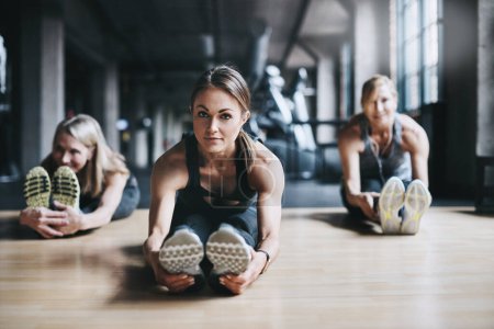 Photo for Preparing their bodies for a workout. Full length shot of three attractive and athletic women stretching before their workout in the gym - Royalty Free Image
