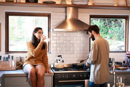 Photo for Cooking, couple and wine in a kitchen at home with food at a stove drinking alcohol. Young woman, man and drinks in a house together making dinner with bonding, love and care for eating a meal. - Royalty Free Image