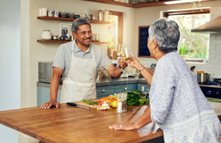 Photo for Cheers, wine and old couple in kitchen, cooking healthy food together with smile, diet and health. Toast, senior woman and man with drinks in glass, meal prep and happiness with love in retirement - Royalty Free Image