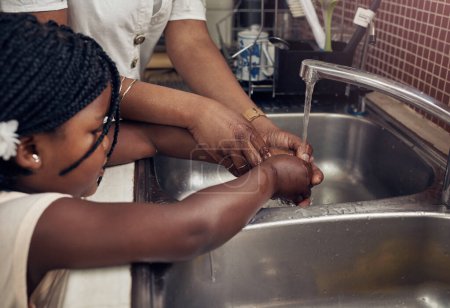 Téléchargez les photos : Mains, évier et maman avec enfant, enseigner ou aider à se laver avec du savon, de l'eau ou nettoyer pour arrêter les germes. Maison familiale africaine, mère et fille au robinet pour le nettoyage, aider la main ou le bien-être dans la maison. - en image libre de droit