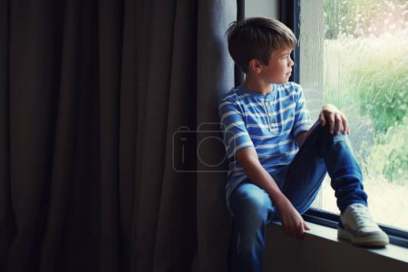 Photo for Boy child, rain and thinking by window with sad face, mental health and mockup space in home. Male kid, raining and think by glass with depression, mock up or fear with problem, winter and frustrated. - Royalty Free Image