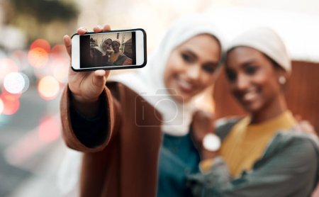 Photo for Muslim woman, friends and selfie with phone in city for travel, urban adventure or post for social media app. Islamic women, smartphone photography and profile picture on internet, web or blog in cbd. - Royalty Free Image