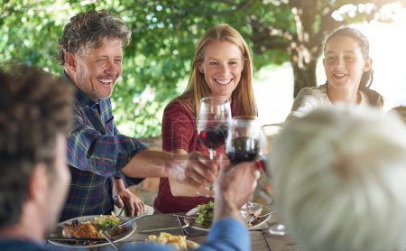 Téléchargez les photos : Famille, groupe et verre de vin pour porter un toast à table pour la célébration, la nourriture et les amis au déjeuner. Hommes, femmes et sourire ensemble pour célébrer avec de l'alcool, des lunettes et du soutien à la fête, au dîner ou à la maison. - en image libre de droit
