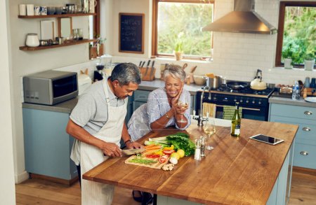 Photo for Cooking, happiness and old couple with wine at kitchen counter, healthy food and marriage bonding in home. Drink, glass and vegetables, senior woman and man with vegetable meal prep and retirement - Royalty Free Image