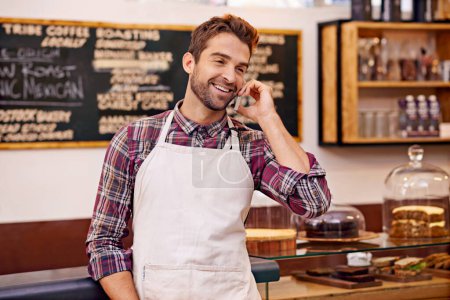 Téléchargez les photos : Livraison sûre. un barista parlant sur un téléphone portable dans un café - en image libre de droit